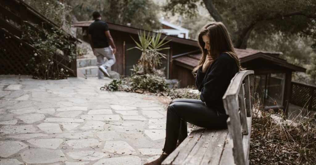 Una persona sentada sola en un banco, mirando hacia el horizonte, simbolizando el agotamiento emocional tras una separación reciente.