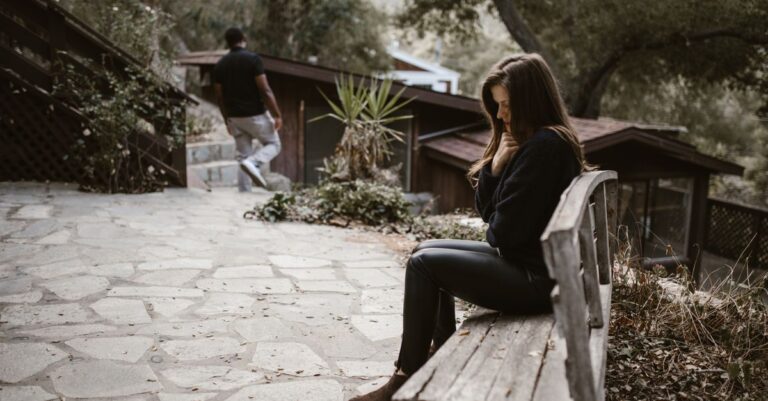 Una persona sentada sola en un banco, mirando hacia el horizonte, simbolizando el agotamiento emocional tras una separación reciente.