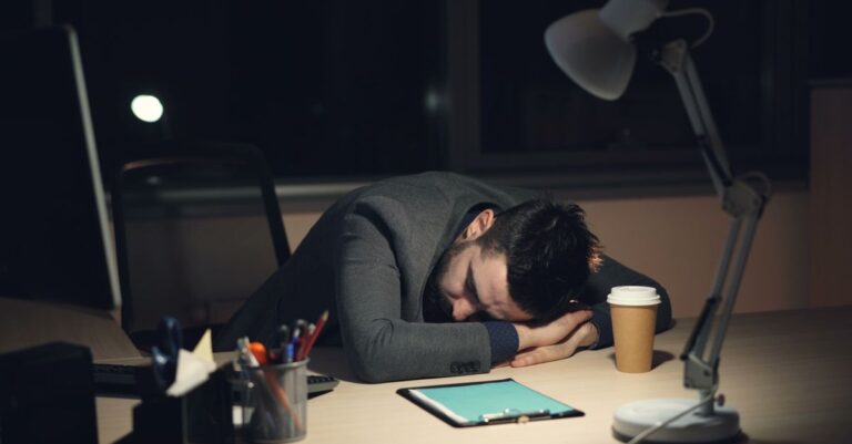 Un trabajador agotado en su oficina, reflejando el impacto del cansancio emocional en el entorno laboral.