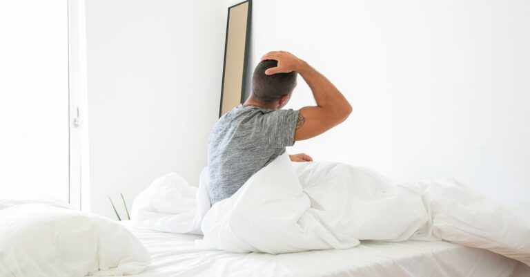 Una persona despertando en la cama con expresión de preocupación, reflejando la lucha interna con pensamientos negativos al inicio del día.
