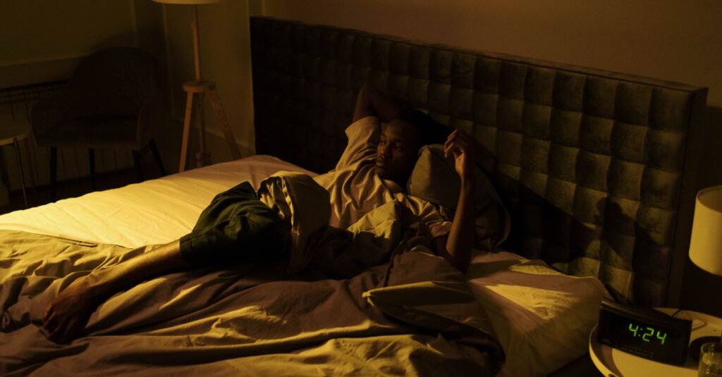 Persona con expresión de frustración en la cama durante la noche, simbolizando el impacto de la ansiedad y el estrés en el sueño.