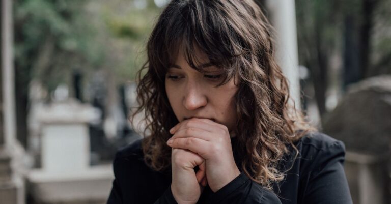 Una persona sentada en un parque con expresión melancólica, simbolizando la tristeza que afecta la capacidad de disfrutar actividades.