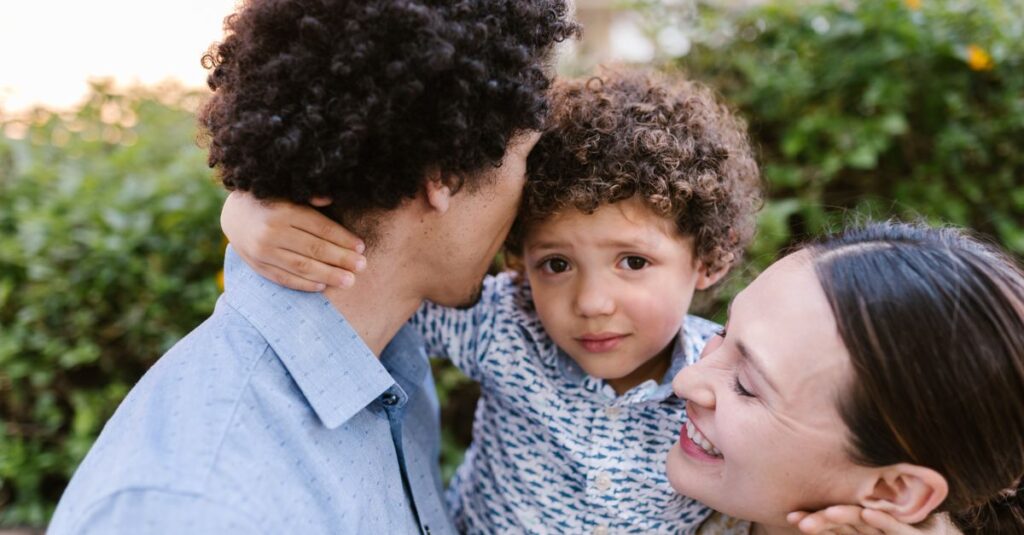 Una familia sentada en el sofá, compartiendo un momento de risa y conexión emocional, representando la importancia de la relación entre padres e hijos.