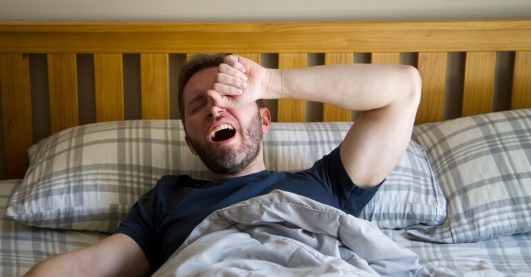 Persona cansada despertando en la mañana, simbolizando los efectos emocionales del agotamiento diario.