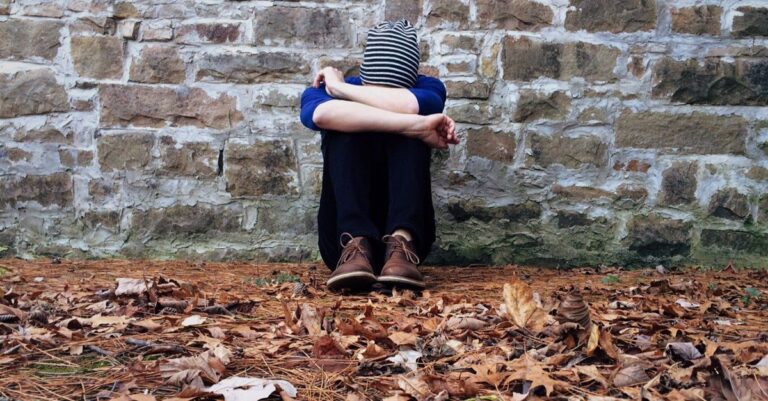 Una persona reflexionando en un entorno natural, simbolizando la tristeza y la adaptación a cambios en la vida.