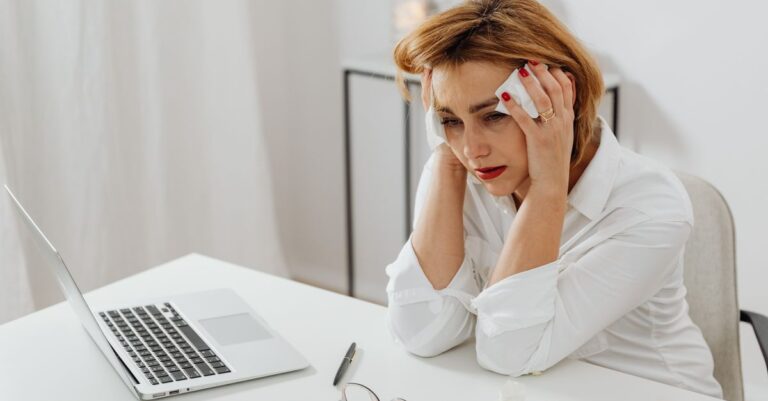 Una persona sentada en un escritorio con expresión triste, reflejando cómo la tristeza puede afectar la motivación laboral.