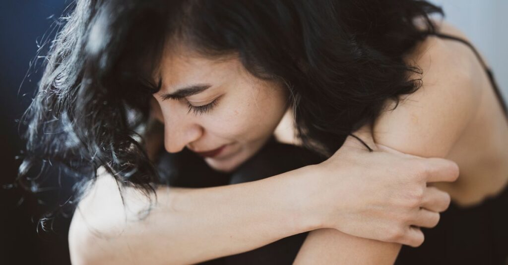 Una persona sentada en un banco, mirando al horizonte con expresión melancólica, simbolizando la tristeza constante y su relación con la depresión.