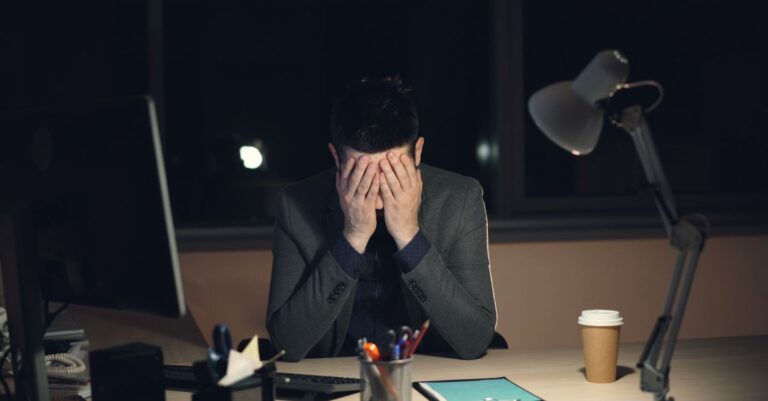 Una persona mirando hacia su computadora con expresión de preocupación, simbolizando la ansiedad laboral.
